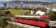 Image of the Wellington Cable Car in the foreground on a sunny day, with Kelburn Park and Wellington City and Harbour in the background