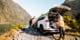 Person standing beside an open GO Rentals SUV trunk on a mountain road